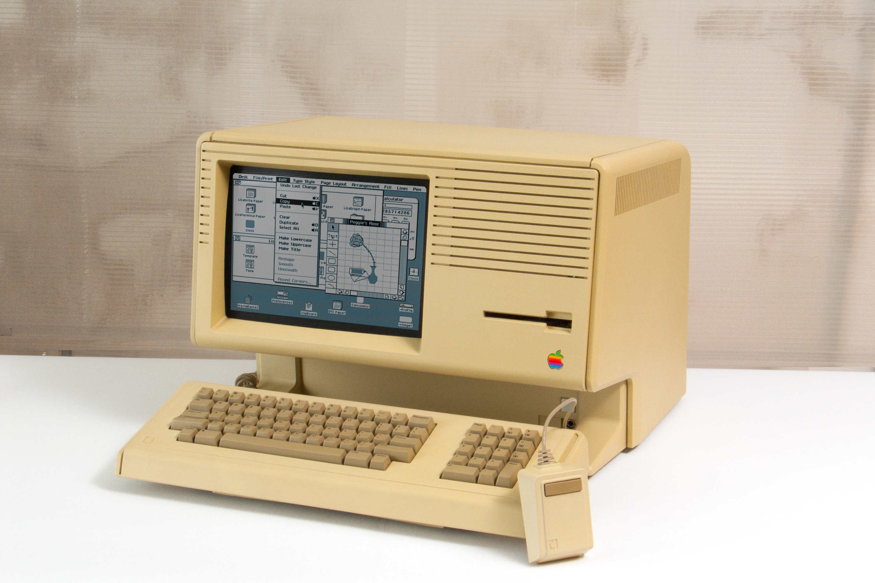 Компьютер Macintosh на столе под углом, отображающий графический пользовательский интерфейс компьютера.