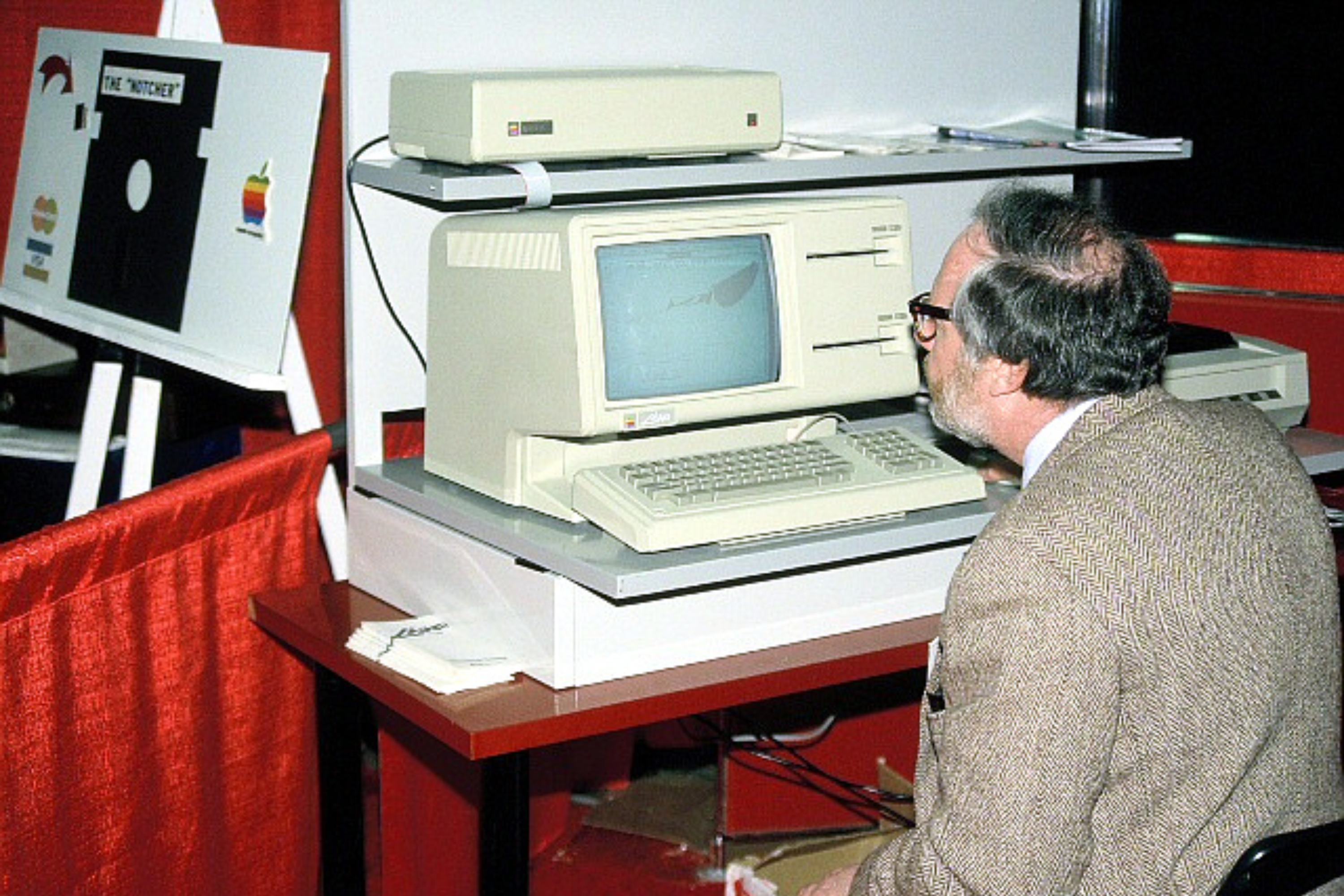 Изображение компьютера Apple Lisa на конференции Apple в Бостоне, мужчина сидит за компьютером, чтобы проверить, как он работает.