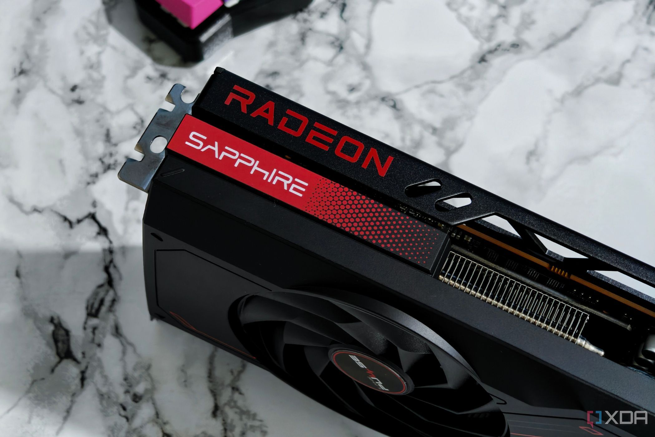 Изображение графического процессора AMD Radeon RX 7700 XT, стоящего на столе с мраморной отделкой.